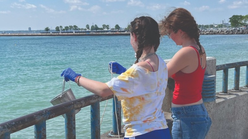 Two people collecting water samples from Lake Michigan.