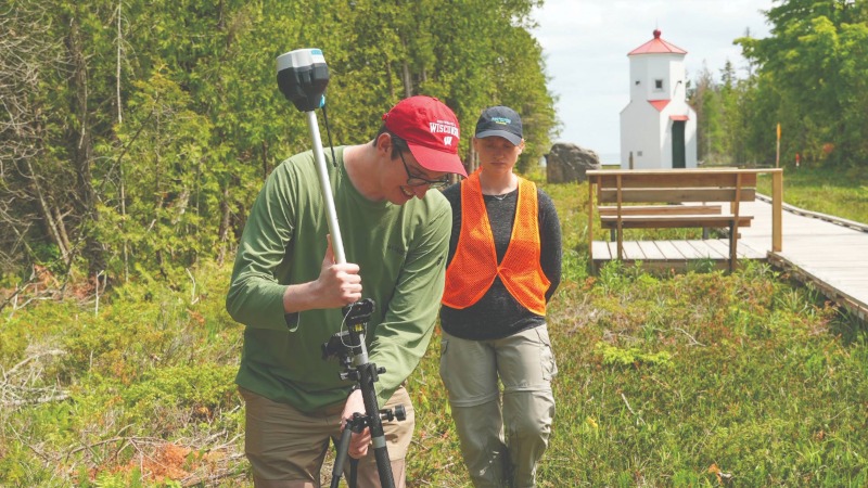 A person putting a measuring device onto a tripod.